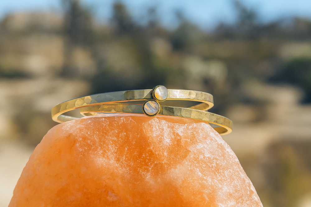 Gold bracelet on a rock with a blurred natural background